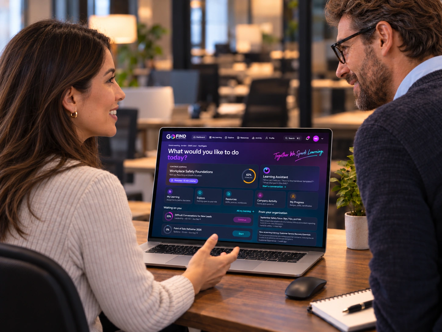 Two colleagues discussing the Go Find Learning platform on a laptop